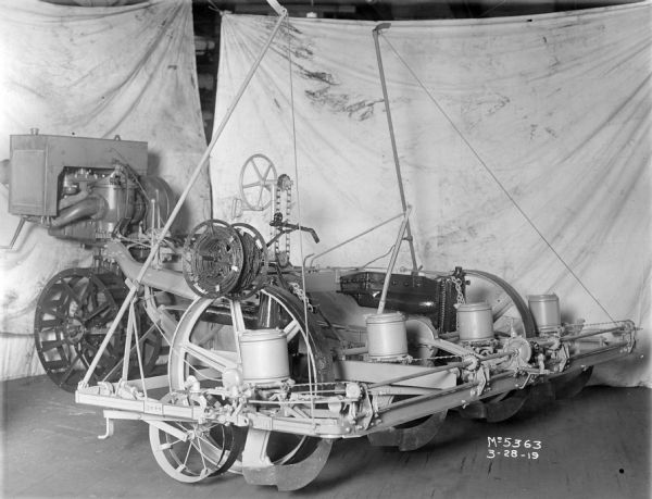 Engineering photograph of an experimental four-row planter.  The original caption reads: "In this four-row planter development the seeding mechanism was driven by the power take-off and a power-lift in connection with the winch arrangement raised and lowered the planting unit. The location of the seat placed the operator's back uncomfortably close to the motor. This job did not get past the experimental stage."