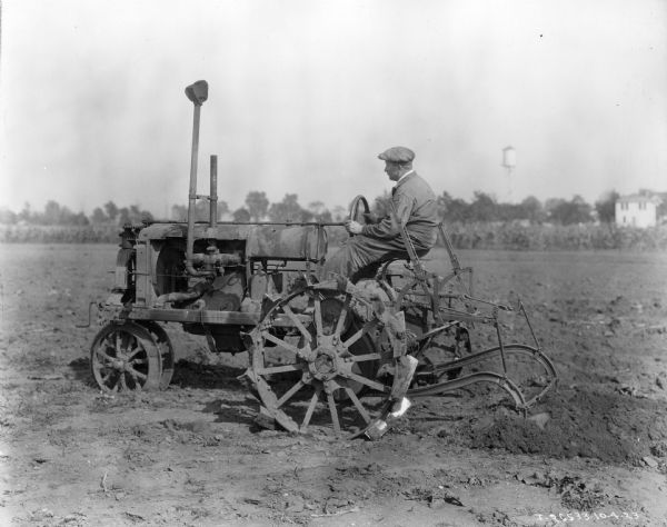 Man operating an experimental(?) Farmall Regular tractor with attached plow.