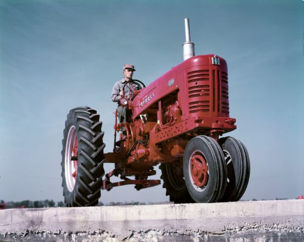 Color photograph of a man operating a McCormick Farmall 400 tractor.