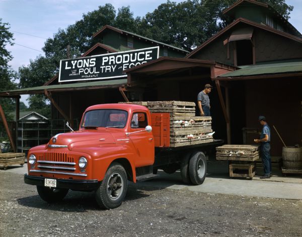 View of a man delivering chickens to Lyons Produce, Poultry and Eggs with an International L-160 truck.