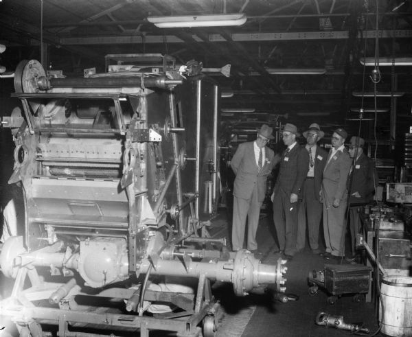Original caption reads: "E.R. Zimmerman, left, St. Cloud district manager, and four dealers and customers watch a No. 141 combine [harvester-thresher] 'come to life' on the assembly line during tour of East Moline Works. On the day of this tour, 32 No. 141s and 60 No. 64s came off the assembly line."