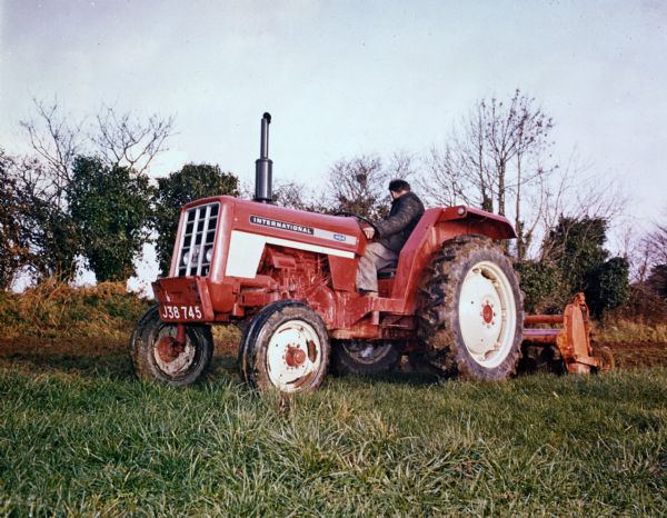 Man plowing a field with an International 454 tractor in a field in Great Britain.