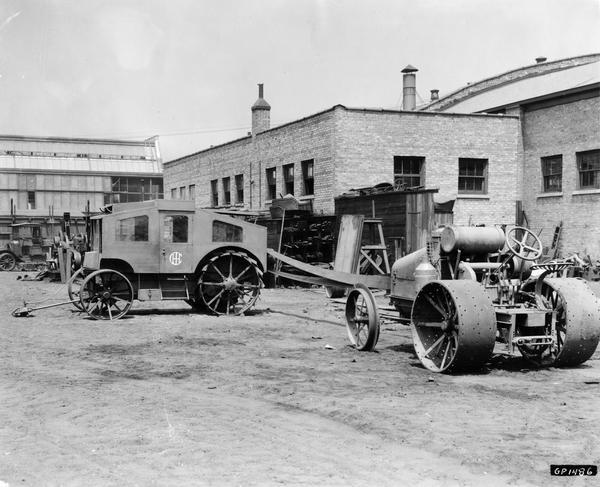 Engineering photograph of an International 8-16 tractor providing belt-driven power to an enclosed trailer with the International Harvester logo on its door. The trailer may contain equipment used to measure the power delivered by the tractor via its power-takeoff. A note with the print reads "dynamometer." The machines are parked in a factory yard.