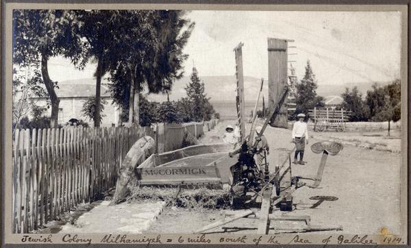 Children looking at a McCormick reaper parked on the side of a road in what is now Israel. The caption reads:  "Jewish Colony Milharuiyeh - 6 miles south of the Sea of Galilee, 1914."