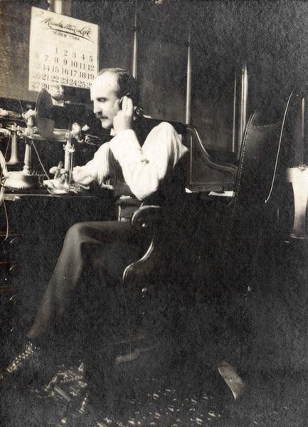 J.W. Wischart talking on a telephone in the office of International Harvester's general agency building in Fort Wayne, Indiana.