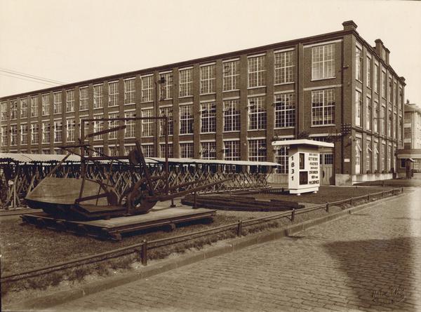 International Harvester's Neuss Works in Neuss, Germany. A reproduction reaper and a sign in front of the building commemorate the one-hundred year anniversary of the invention of the reaper by Cyrus McCormick (also know as the "reaper centennial").