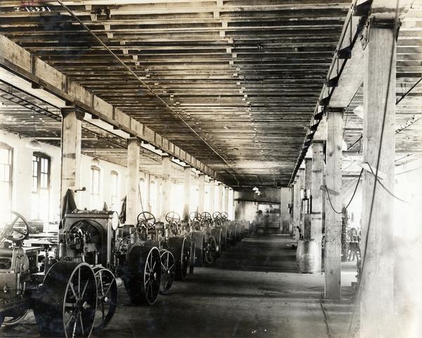 Partially assembled International 8-16 tractors lined up inside International Harvester's Tractor Works (?) (factory).