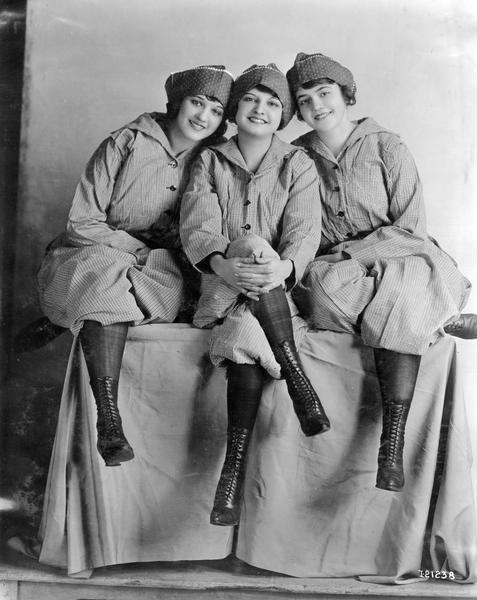 Studio portrait of three female International Harvester factory workers posing for the camera. The women may have worked at one of the company's twine mills.