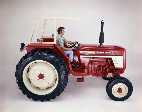 Color photograph of a man sitting on an International 574 tractor in a studio. The tractor was built in Great Britain.