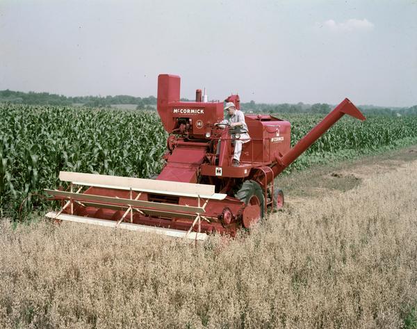 Man operating a McCormick No. 141 harvester-thresher (combine) in a field.