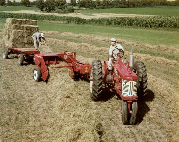 Slightly elevated view of two men baling hay with a Farmall tractor and McCormick hay baler.