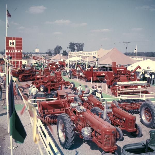 Elevated view of International Harvester's exhibit of agricultural machinery at the Wabash plowing contest. Includes a Farmall 400 tractor (with Electrall?), combines (harvester-threshers) and crawler tractors (TracTracTors), and a version of International Harvester's "red pylon" with the word "Welcome."