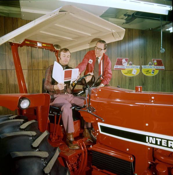 Color photograph of an International dealer working on the sale of an International tractor with a prospect.