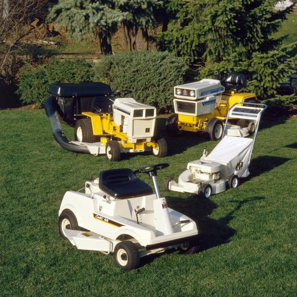Color photograph of International 55, 80, and 1650 Cadet lawn tractors and a push mower.
