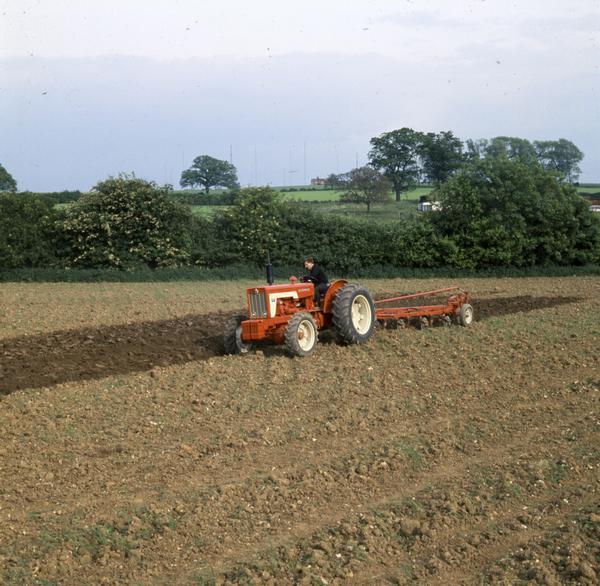 Color photograph of a man plowing a field in Great Britain with a McCormick 634 H-W-D tractor.