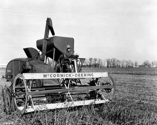 Man testing the model 123-SP (self-propelled) combine (harvester-thresher) in a field. The machine was International Harvester's first self-propelled combine.