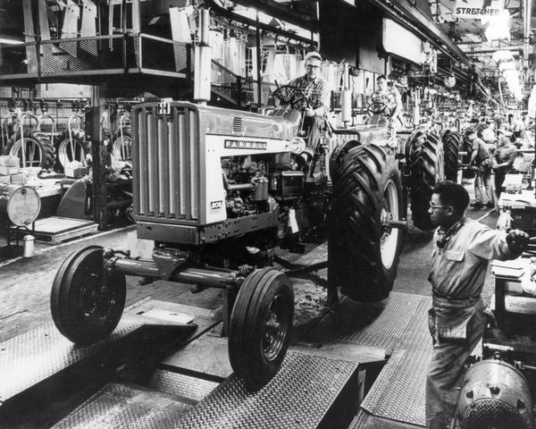Factory workers on a Farmall 806 tractor assembly line.