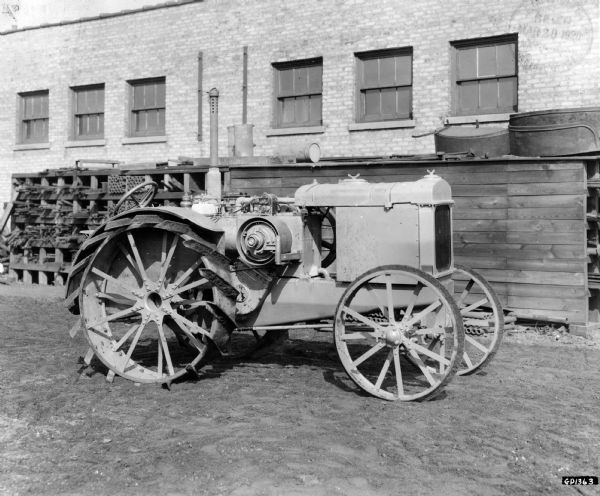 Engineering photograph of an experimental tractor in a yard outside of a factory.
