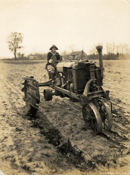 Woman operating a Farmall Regular tractor in a field in New Zealand.