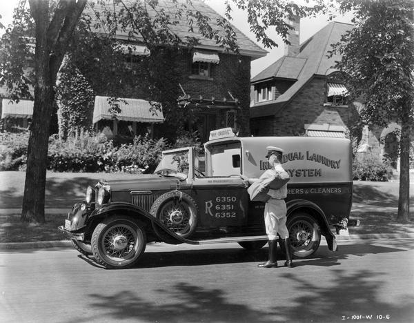 A delivery man getting into an International truck used by the Individual Laundry System laundry and cleaners. A sign on top of the truck asks "Why - Drudge". The truck is parked outside a suburban home.