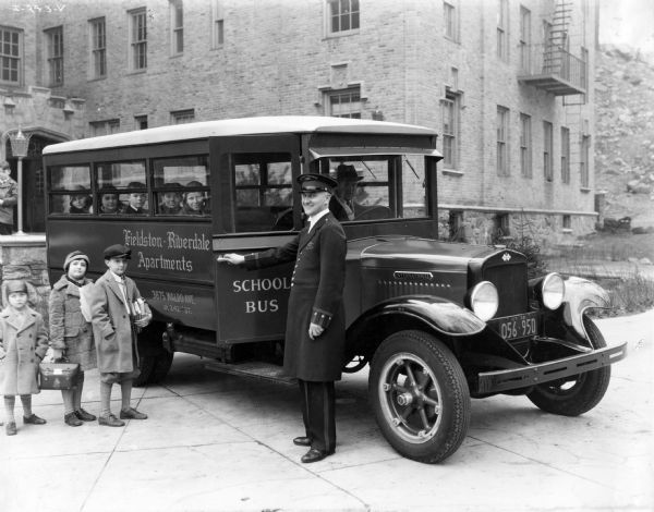 Children boarding an International A-3(?) school bus as the driver stands by. The bus served the Fieldston-Riverdale apartments in New York.