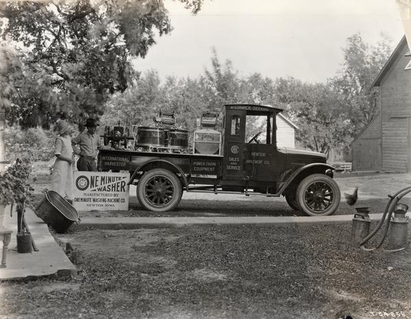 Curt Moore selling "one minute" washing machines to a farmer's wife.  The washing machines are loaded in the back of an International "Red Baby" truck. The Oneminute Washing Machine Company was based in Newton, Iowa.