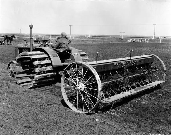 Farmer planting with a W-30 tractor and a 28-marker grain drill. The equipment was owned by Frank Gobert in Otterburn, Manitoba, Canada. The original caption reads: "The land in this part of the country is extremely light and it is necessary to put on the extensions shown to prevent the tractor from sinking to an undesirable depth." Horses are in the background.