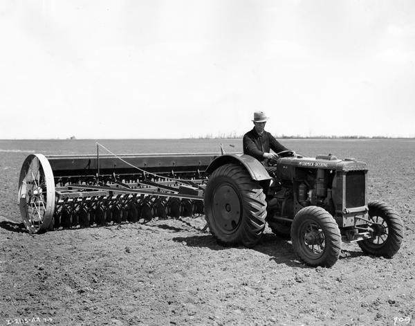 Farmer operating a McCormick-Deering W-12 tractor and grain drill.