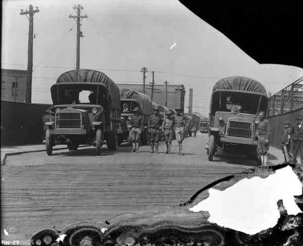 U.S. soldiers standing in a street with military trucks parked along a curb near the McCormick Works. The truck bodies were likely built under military contract at the McCormick Works.