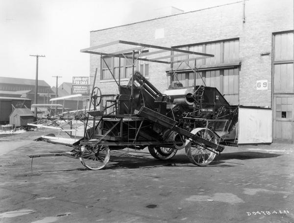 McCormick-Deering no. 7 harvester-thresher (combine) in a factory yard. This model features a bagging platform located high on the machine and a single-wheel turntable type of forecarriage.