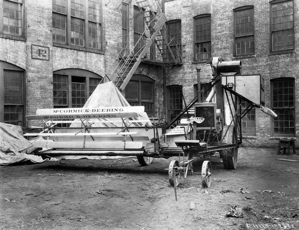 McCormick-Deering no. 8 harvester-thresher (combine) in a factory yard. Original caption reads: "View of the No. 8 harvester-thresher as it is still currently manufactured. The machine is now sold equipped with auxiliary engine and forecarriage."