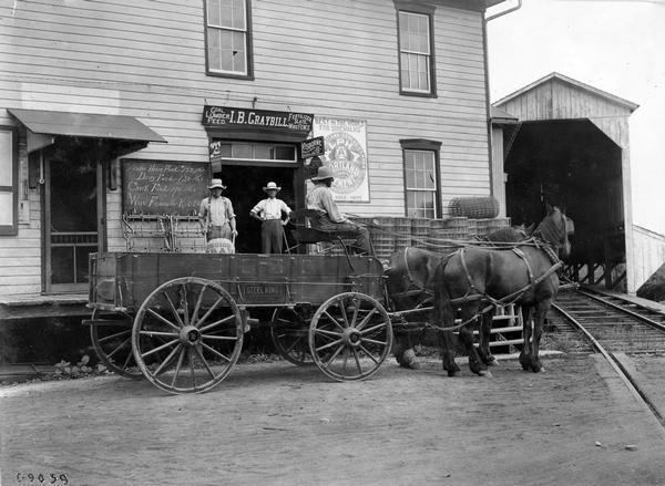 Men posing for the camera while loading sacks of feed into a horse-drawn Steel King wagon in front of the I.B. Graybill general store.