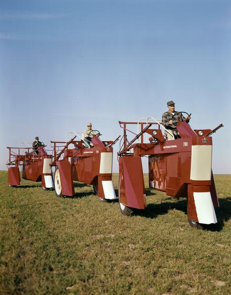 Color photograph of three men operating International 660, 770 and 780 high clearance carriers in a field.