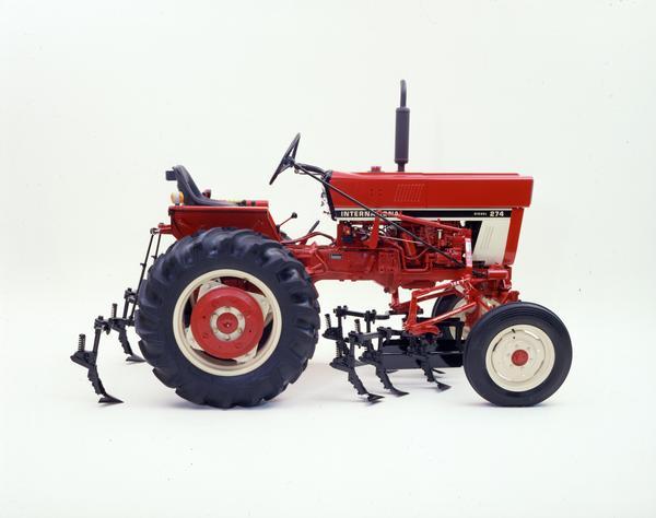 Color photograph of an International 274 tractor with mounted No. 144 cultivator in a studio.