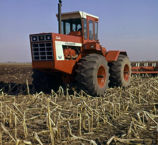 View towards a farmer operating an International 4568 Turbo tractor in a cornfield.