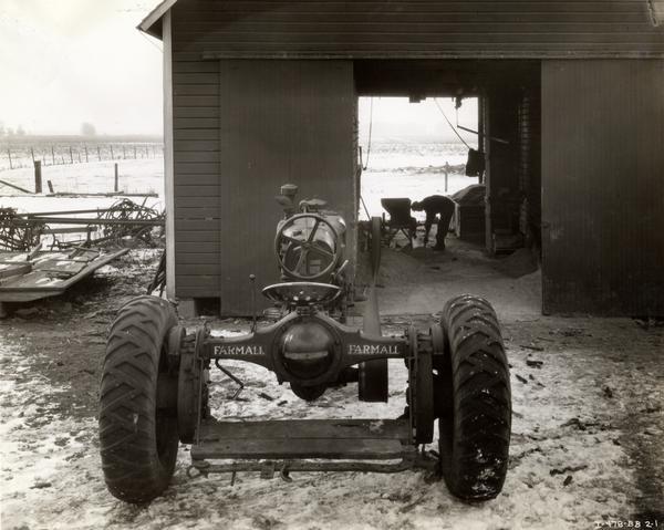 McCormick-Deering Farmall F-30 tractor parked in front of a barn while farmer A.B. Wicks grinds corn with a McCormick-Deering feed grinder.