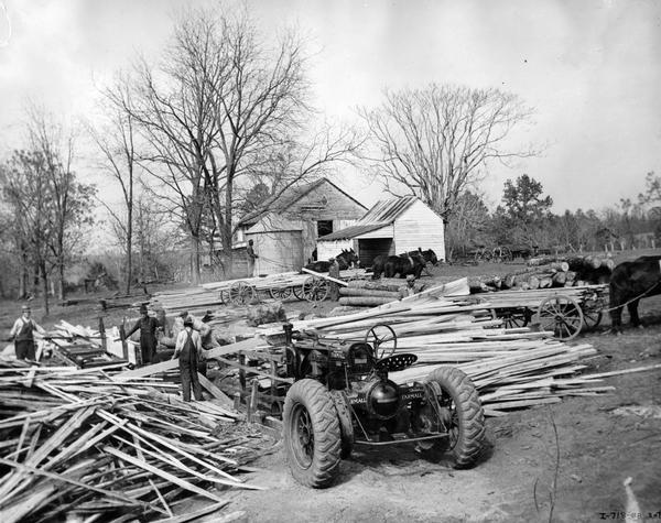 Men operating a belt-driven sawmill powered by a McCormick-Deering Farmall F-30 tractor on the property of W.A. Moorhead.