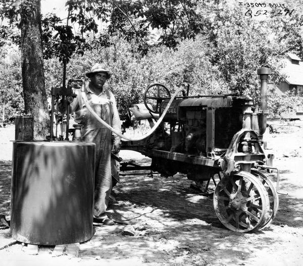 Farmer Clark Cutter refueling his McCormick-Deering Farmall Regular tractor.