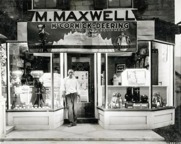 McCormick-Deering dairy equipment dealer Marrin Maxwell standing in front of his store. Cream separators and other dairy equipment are on display.