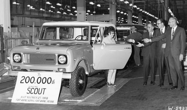 Press release photograph of the 200,000th International Scout truck rolling off of the assembly line. Original caption reads: "Almost eight years to the day after the first one was produced, the 200,000th Scout compact utility vehicle was driven off the assembly line at the Fort Wayne Works of International Harvester Company's motor truck division. In ceremonies heralding the milestone, the Scout is greeted by its new owner, Mrs. June Pontello, an employee at the Works. Mrs. Pontello's Scout is the first of the new models just introduced by International. Sharing the important moment with her are (from left) Homer C. Keck, manager of the Fort Wayne sales branch; R.E. Mills, superintendent of the Scout assembly line at the Works; and H.A. Ehrman, Works manager."