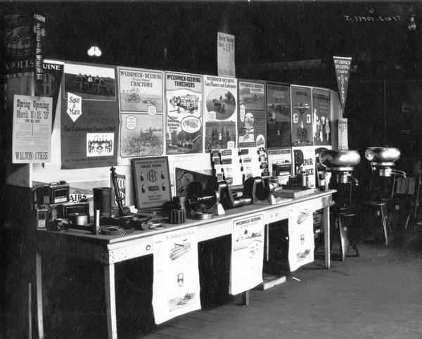McCormick-Deering cream separators, farm equipment parts, accessories, advertising literature and posters arranged on a table, possibly for a state fair. A handbill posted on the exhibit bears the name "Walton & Sykes."