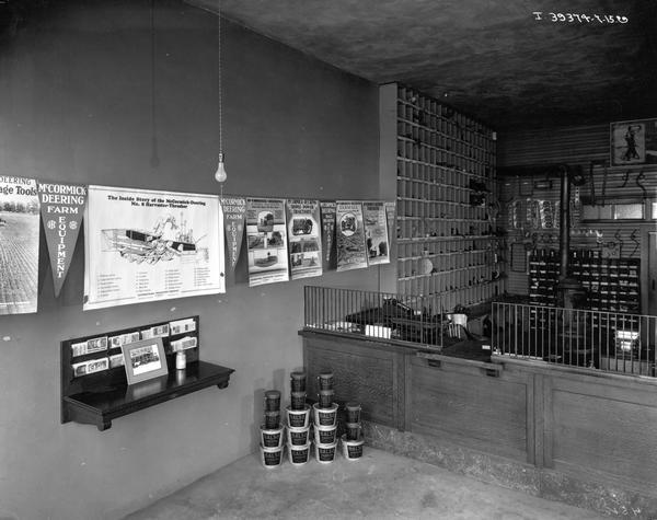 Parts desk at a McCormick-Deering farm equipment dealership. Advertising posters, parts bins and a literature rack are mounted on the walls.