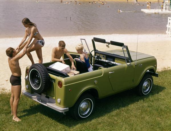 Color advertising photograph of two young couples in swimsuits getting out of an  International Scout pickup truck near a public beach.