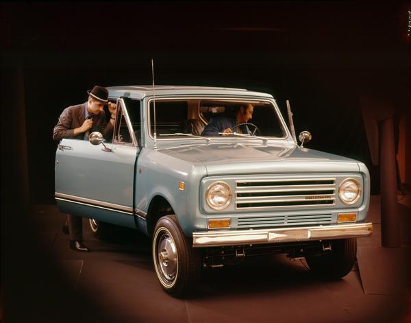 Color advertising photograph of two men getting into a Scout II pickup truck in a studio.