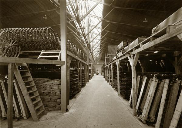 Implement parts stacked in a storage room at an International Harvester branch in Germany. Caption below photograph reads: "International Harvester Company m.b.H., Hamburg 27, Grossmannstrasse 114. Maschinenlager".