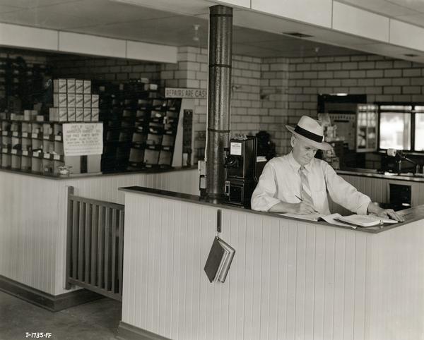 K.M. Fores attending to paperwork at the Rogers Truck & Implement Company, an International Harvester dealership. Mr. Fores was filling in for his son, Lieutenant K.M. Fores Jr. who was called to the army shortly after he had constructed the company.