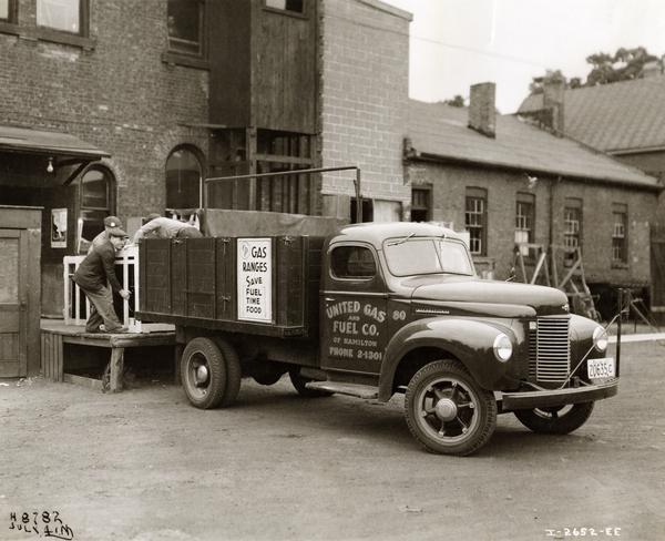 Workers loading items into an International K-4 truck for United Gas and Fuel Company of Hamilton, Ontario, Canada. A sign on the truck reads: "gas ranges save fuel, time, food."