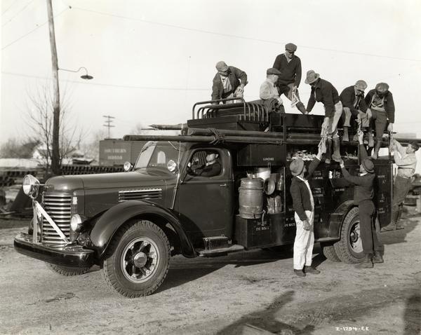 Workers climbing on an International K-7 truck owned by Southern Bell Telephone Company, ready to service customers between Jacksonville and Camp Blanding, Florida.