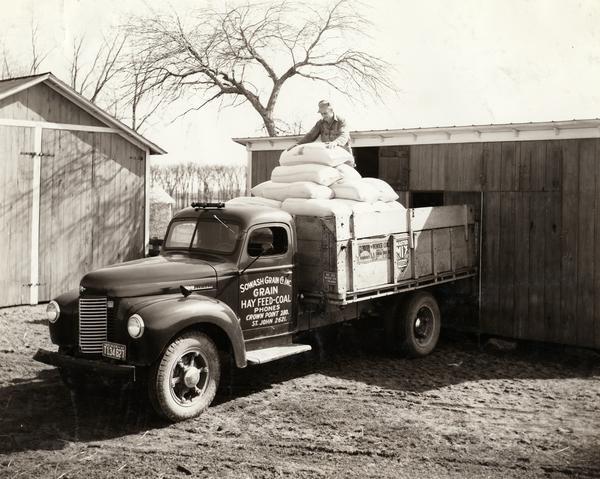 Man loading sacks of millet seed onto an International K-5 truck bound for a Chicago market. The truck was owned by Sowash Grain Co. Inc. of Crown Point, Indiana.