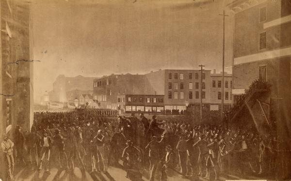 Photograph of an artistic rendering of a rally held at Haymarket Square on May 4, 1886, before the explosion of the bomb. Haymarket Square is at the Intersection of  Randolph and Desplaines streets close to City Hall by the South Branch of the Chicago River. In this scene, thousands have gathered protesting the killing by police officers of two union member McCormick reaper factory workers during a confrontation between the union workers and their replacements the previous day.